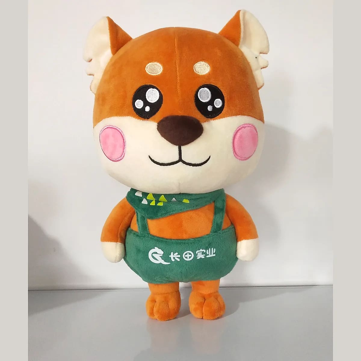 Shiba Inu plush in branded apron — custom plush toys manufactured in Shenzhen by Custom Plush Toy Factory